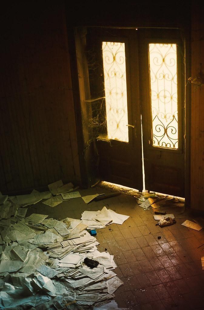 An abandoned room with light streaming through ornate doors