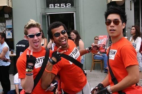 Three men in orange “TEAM” t-shirts outdoors